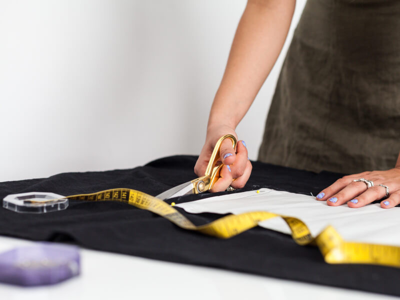 A person is measuring, pinning at cutting fabric at a sewing workshop.